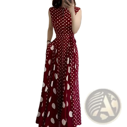 A woman wearing a sleeveless red polka dot French formal maxi dress with large white dots and floor-length design