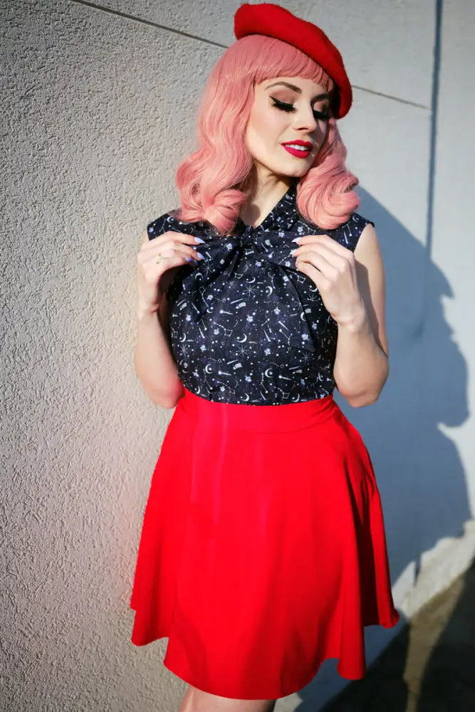 A woman wearing a vintage red skater skirt with pockets and elastic waist paired with a navy blue starry top