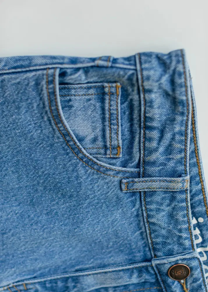 Remi Classic Wash stretch denim midi skirt in medium-wash blue with brown stitching and a classic front pocket