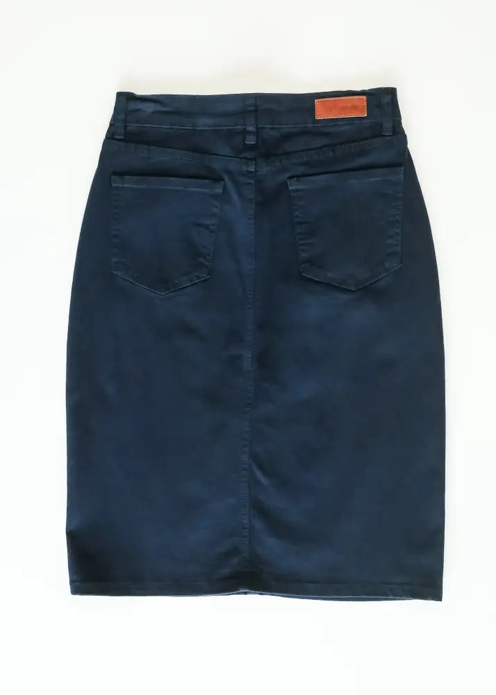 Back view of remi navy high waisted stretch denim midi pencil skirt with two back pockets and brown leather patch