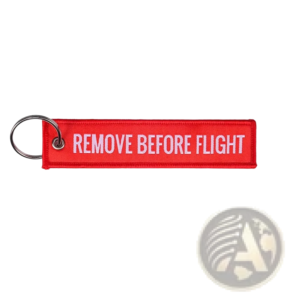 Red embroidered remove before flight keychain with white text and metal ring for aviation safety purposes