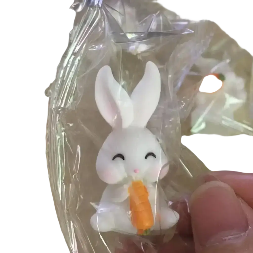 White smiling resin bunny figurine holding orange carrot for easter garden and cake decor