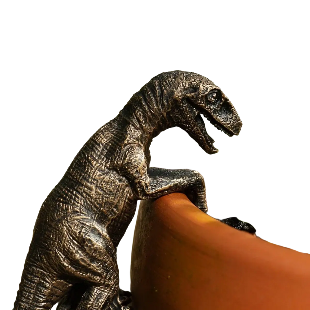 Bronze resin climbing dinosaur flower pot ornament with intricate texture beside terracotta planter
