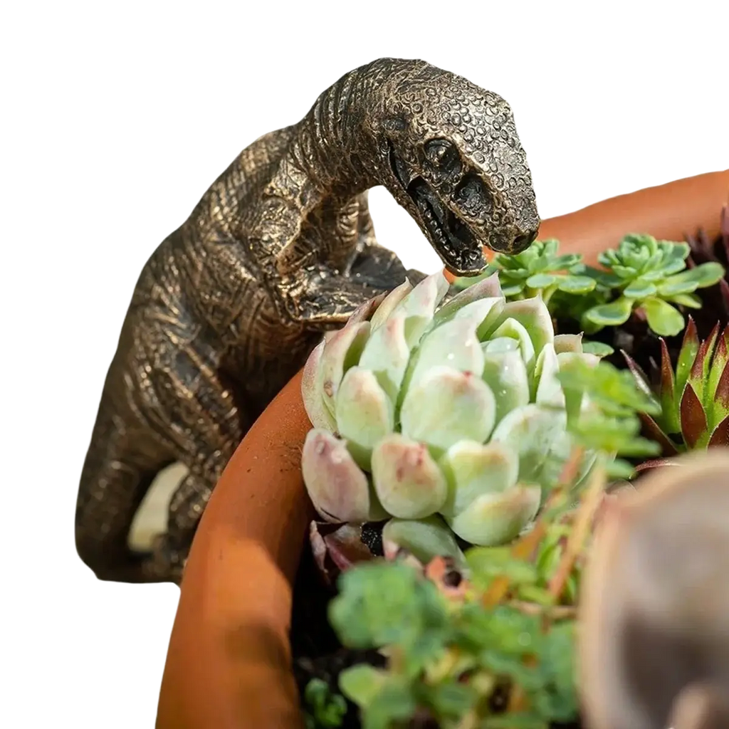Bronze-colored resin climbing dinosaur flower pot ornament with textured design perched on a terracotta pot rim