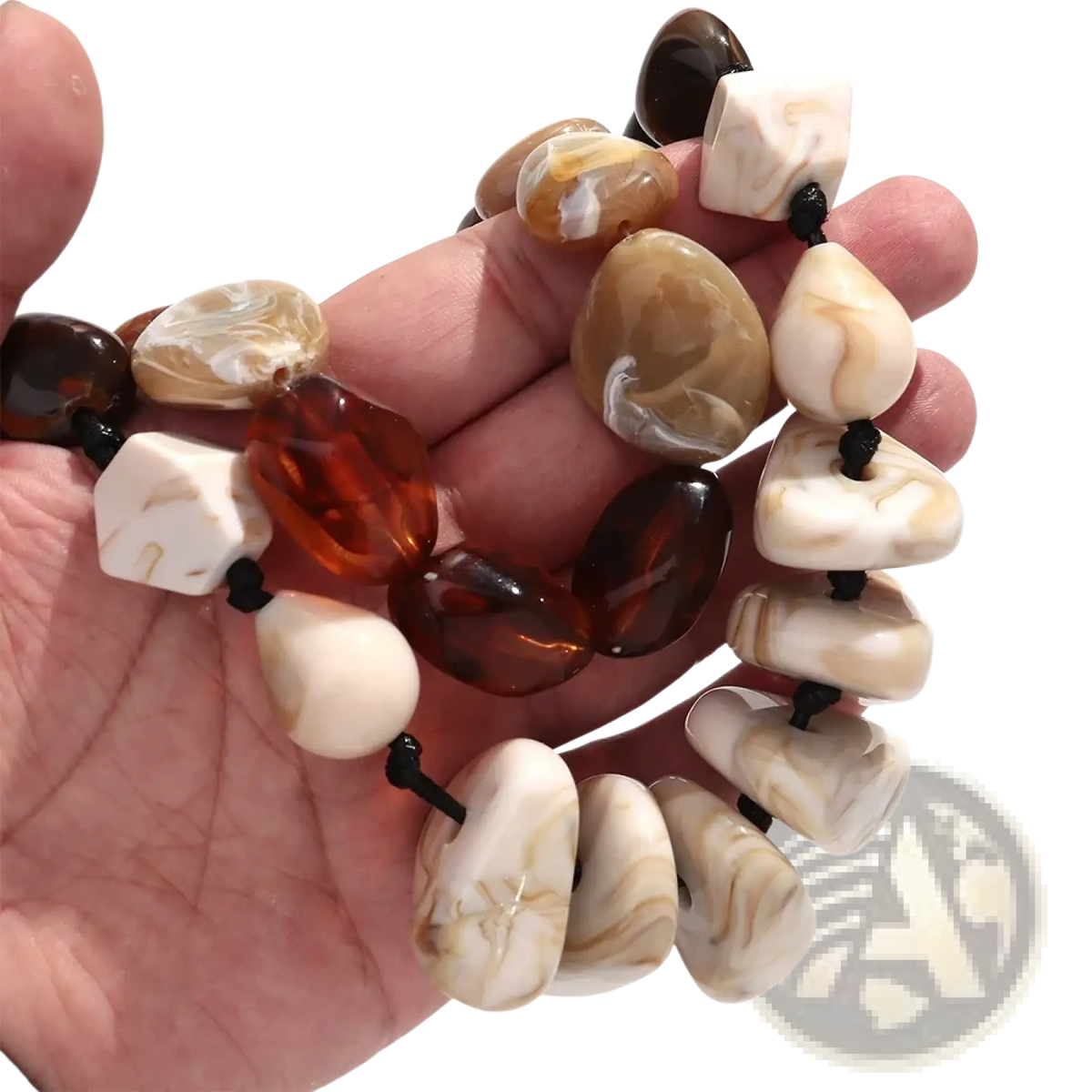 A hand holds a resin geometric marbled beaded choker necklace with amber and cream stones on black cord