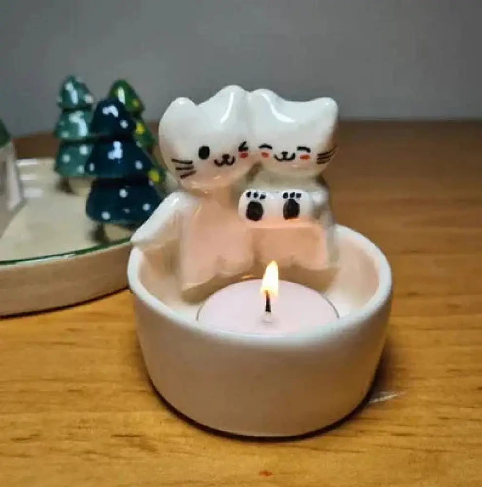 White ceramic candle holder featuring two smiling cat figures cuddling and holding a small tea light candle