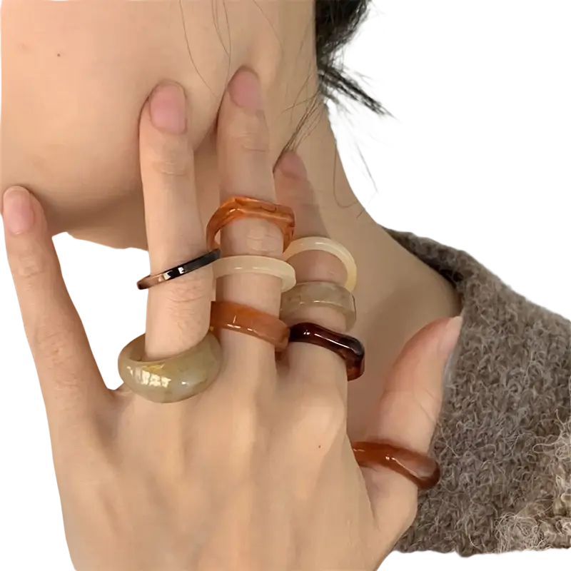 A collection of amber-toned bohemian retro style resin stackable rings with smooth glossy finishes on multiple fingers