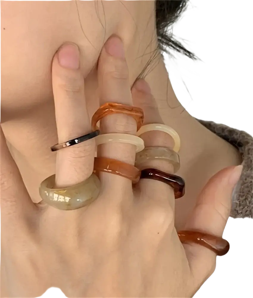A set of bohemian retro style stackable resin rings in amber and black tones with smooth rounded edges worn on fingers