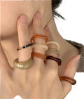 A set of bohemian retro style stackable resin rings in amber and black tones with smooth rounded edges worn on fingers