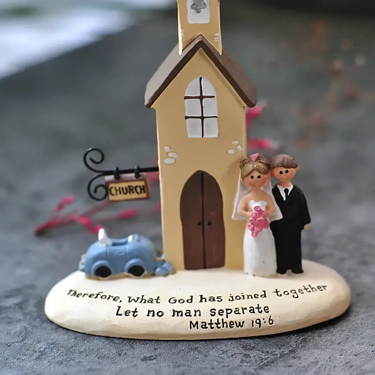 Beige resin wedding church figurine with brown roof bride and groom holding flowers beside blue car anniversary gift