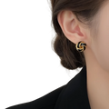Black and gold knot-shaped enamel stud earring with glossy finish in a retro style design