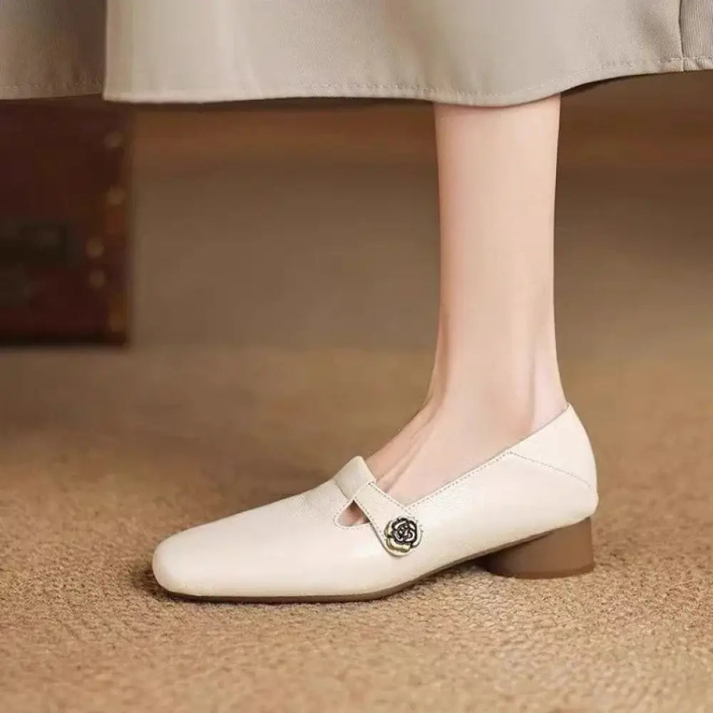 Cream-colored leather mary jane flats with a retro square toe and silver rose-shaped buckle detail