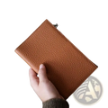 A tan pebbled leather rfid passport holder travel wallet with a silver zipper pull for secure travel