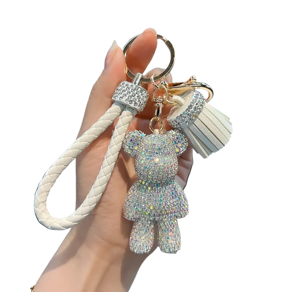 A sparkling white rhinestone bear keychain with braided leather strap and tassel accent