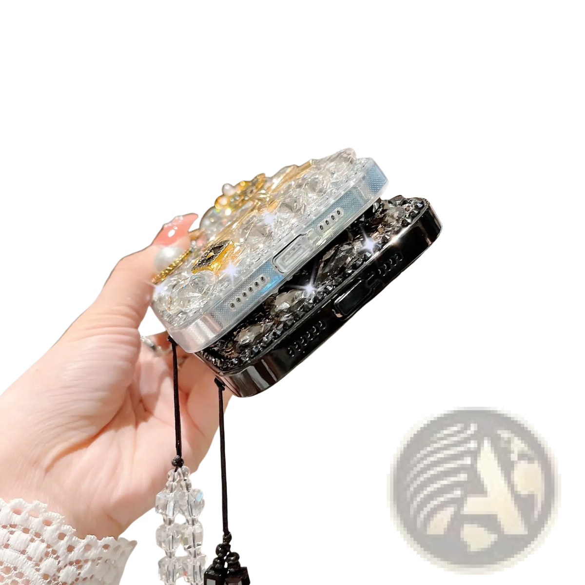 A hand holds two rhinestone bow luxury iPhone cases in silver and black with crystal embellishments and beaded charms