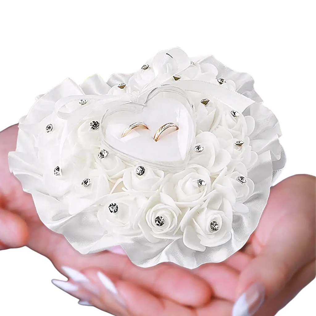 A delicate white rhinestone floral wedding ring pillow with a heart compartment holding two gold rings