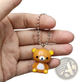 A small orange rilakkuma bear keychain charm with yellow ears paws and a silver ball chain pendant for diy use