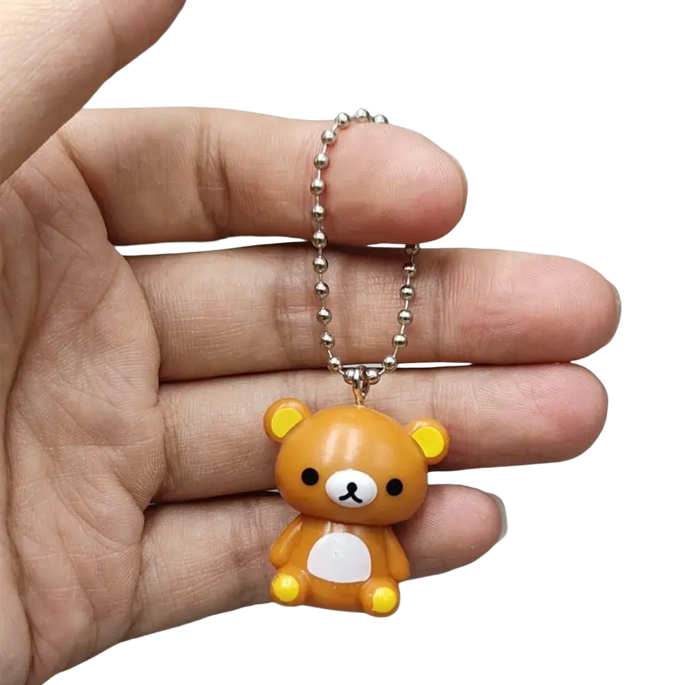 A small orange rilakkuma bear keychain charm with yellow ears paws and a silver ball chain pendant for diy use