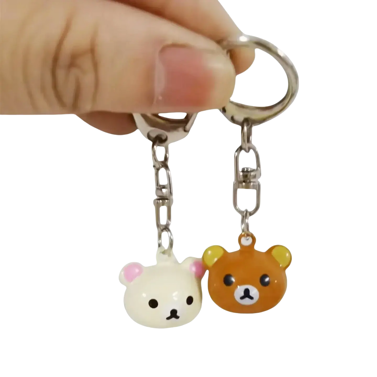 A pair of cute glossy plastic rilakkuma bear keychains in white with pink ears and orange, attached to metal rings
