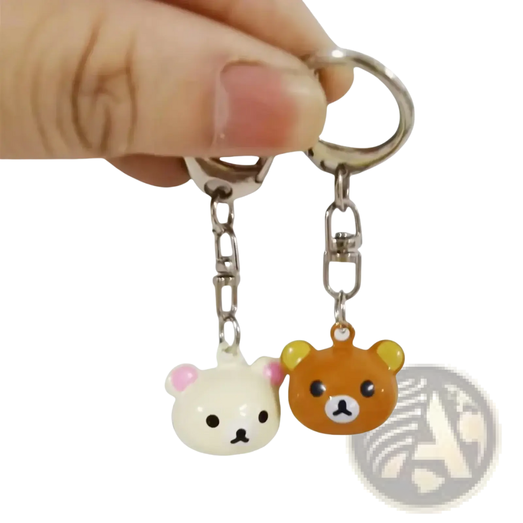 A pair of cute glossy plastic rilakkuma bear keychains in white with pink ears and orange, attached to metal rings