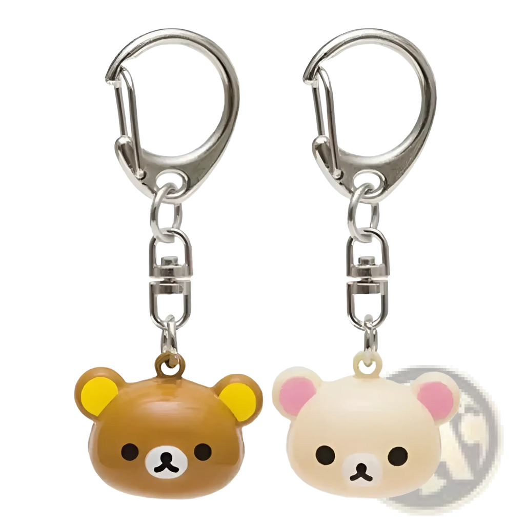 Two rilakkuma bear keychains in brown with yellow ears and cream with pink ears featuring glossy plastic faces