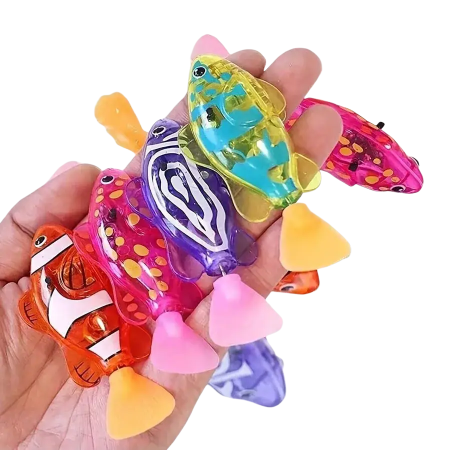 A hand holds colorful translucent robotic fish bath toys with pink fins featuring photosensitive swimming clownfish designs