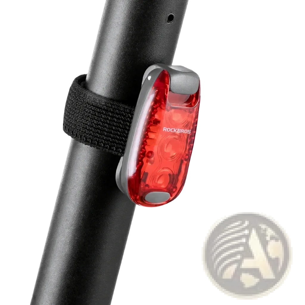 Red translucent rockbros bike tail light with silver metallic frame and black elastic strap showing the back side