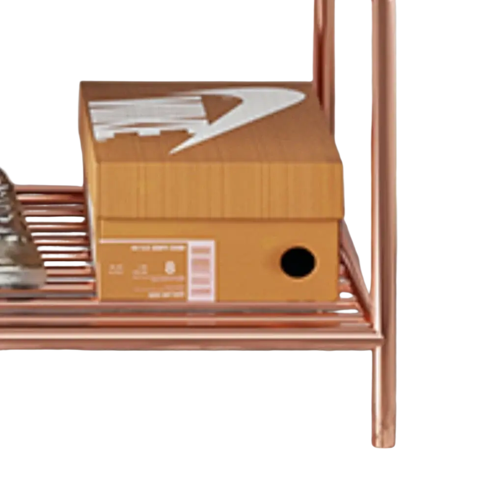 A tan cardboard nike shoebox with white swoosh logo and barcode on a copper rose gold kids clothes rack with bench