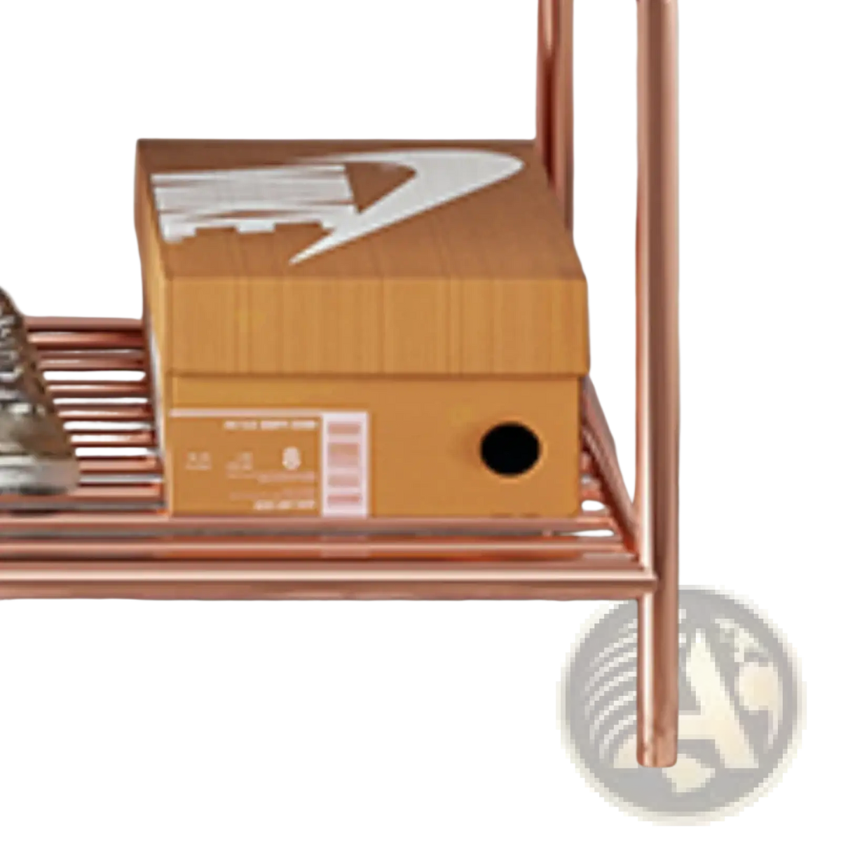 A tan cardboard nike shoebox with white swoosh logo and barcode on a copper rose gold kids clothes rack with bench