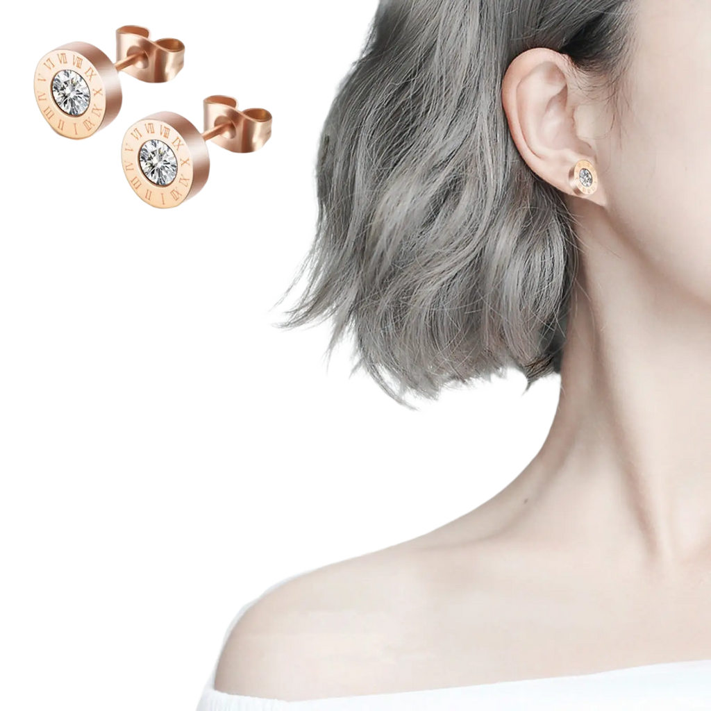 Rose gold roman numeral diamond stud earrings with a central clear gemstone on a circular face