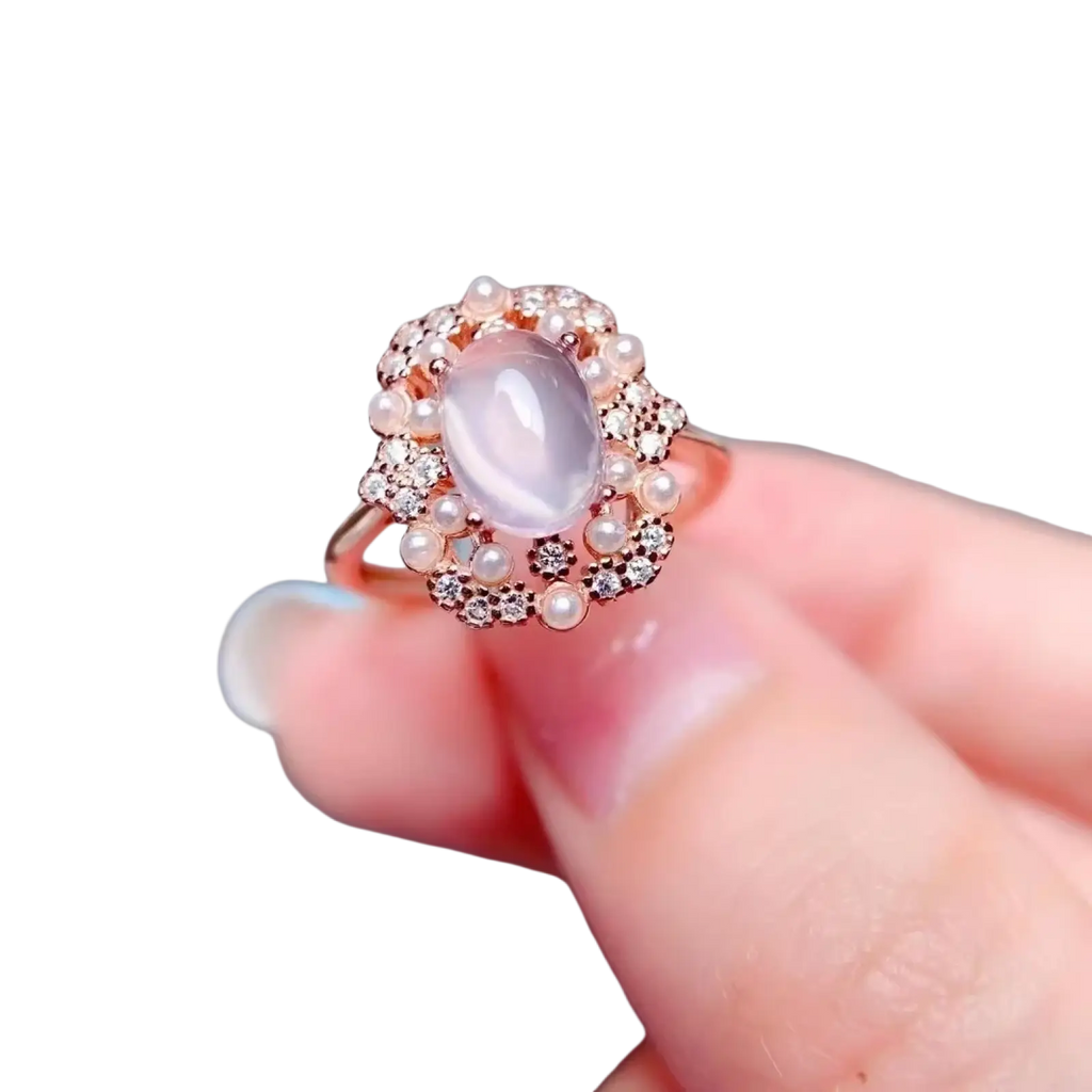 A rose quartz sterling silver ring with an oval pale lavender jade stone surrounded by white pearls and clear diamonds