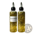 Two clear plastic bottles of 60ml rosemary hair care essential oil with golden liquid and dried rosemary sprigs inside