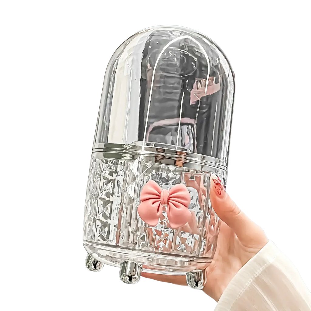 Rotating cosmetic makeup organizer with clear glass dome container featuring pink bow and silver metallic accents