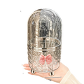 Clear glass hair accessory holder with silver base and pink bow on rotating cosmetic makeup organizer storage box