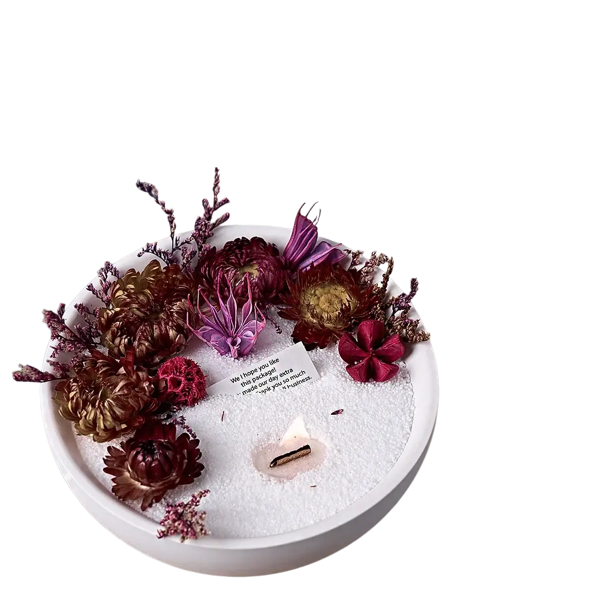 White ceramic candle holder with lit candle in white sand surrounded by dried burgundy flowers in round silicone mold