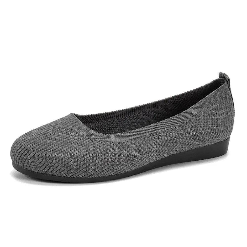 Women’s gray round toe knit mesh slip on flats with black rubber sole and elastic heel tab shown from back side