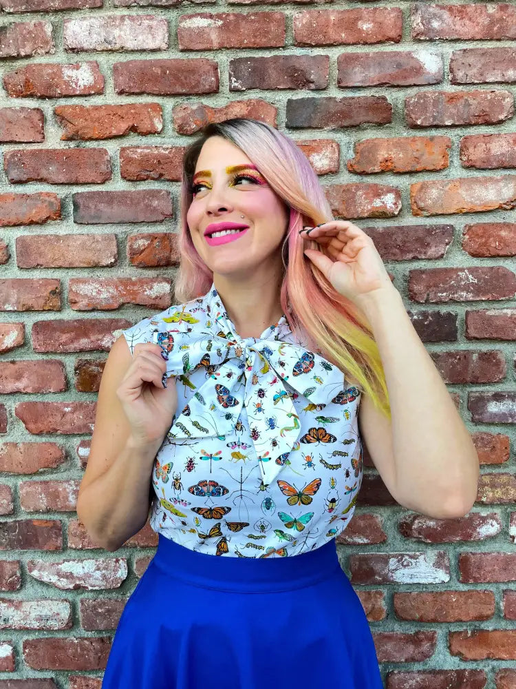 A light blue sleeveless blouse with butterfly and insect print and bow paired with a royal blue retro a-line skater skirt with pockets