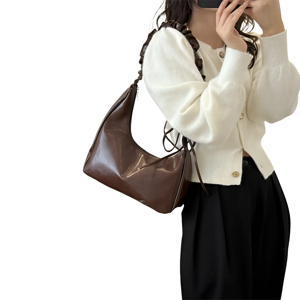 Brown ruched shoulder bag made of patent faux leather featuring a ruffled hobo shoulder strap