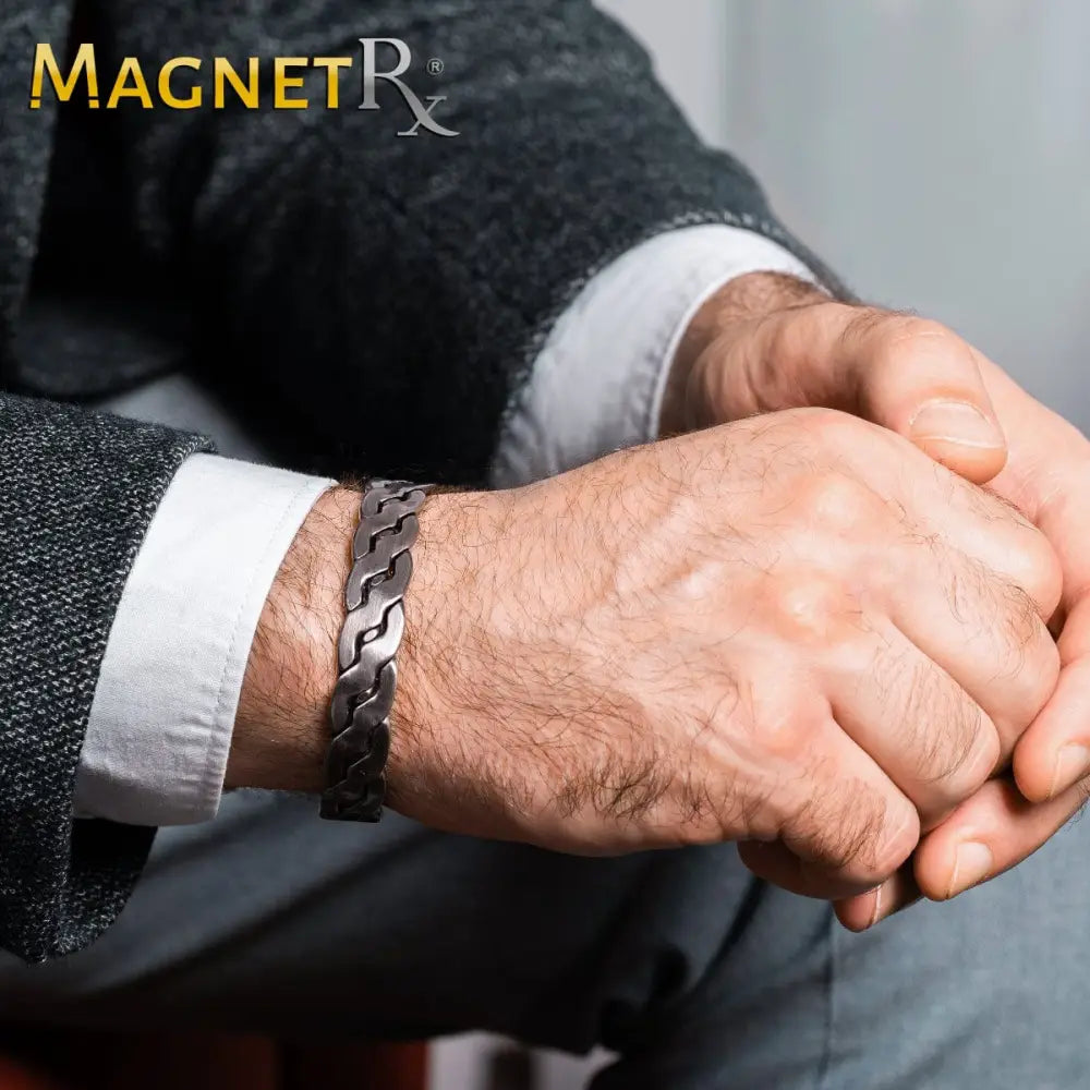 A sleek dark metallic rugged silver braided copper magnetic therapy bracelet with an interlocking chain design worn on a man’s wrist