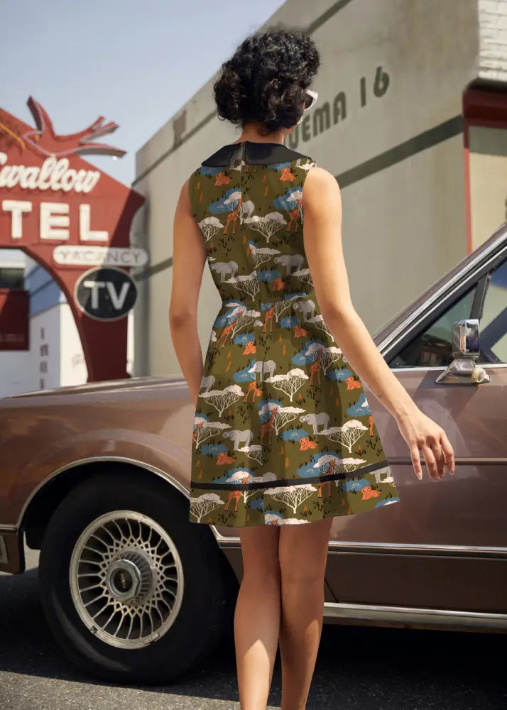 Olive green cotton sleeveless safari print retro dress with black collar and hem featuring stylized animal pattern