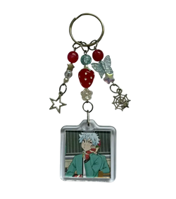 Clear acrylic saiki k beaded anime keychain with white hair character square portrait and dangling charms including stars and berries