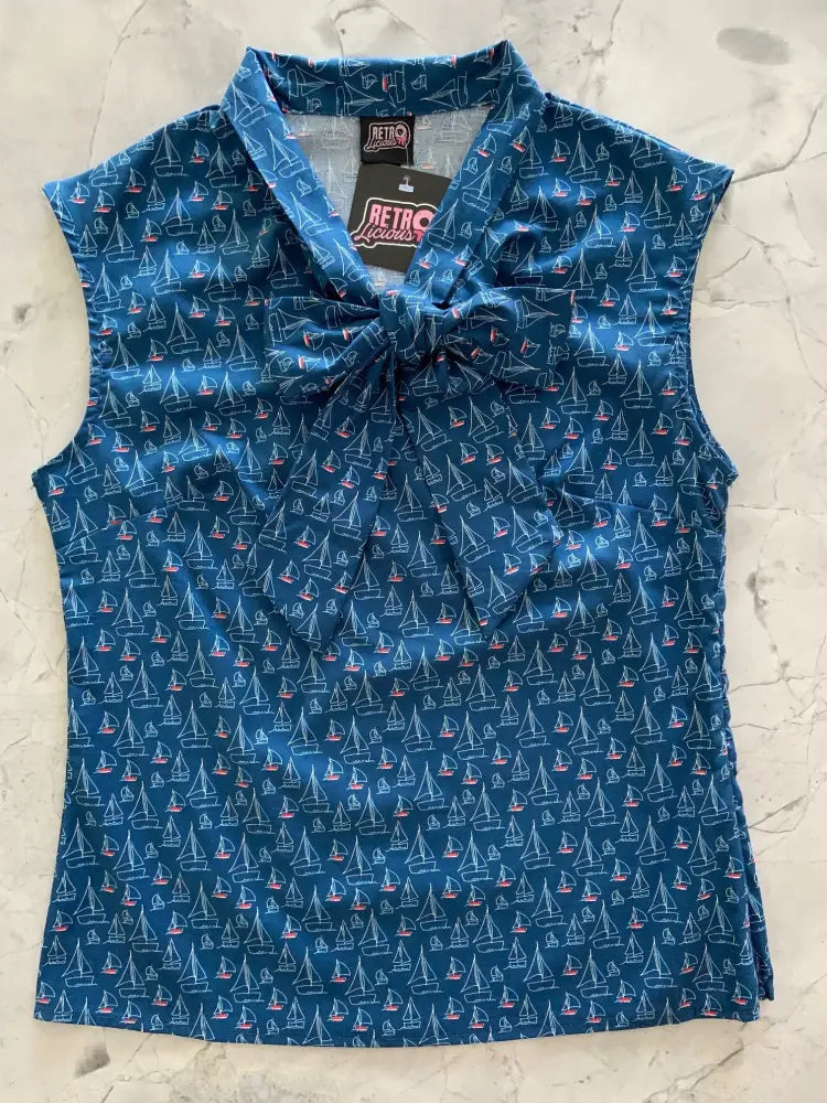 A navy blue sleeveless blouse with vintage white and pink sailboat print and a tied bow at the collar