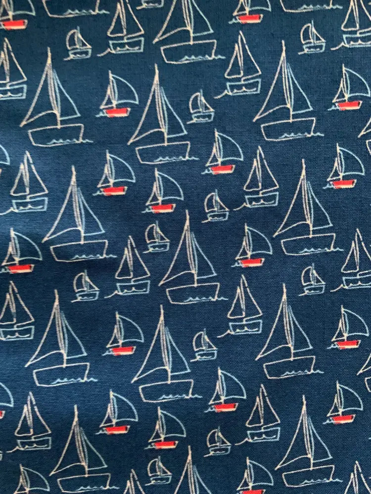 Navy blue vintage sailboat print bow tie blouse featuring white outlined sailboats with red accents on fabric
