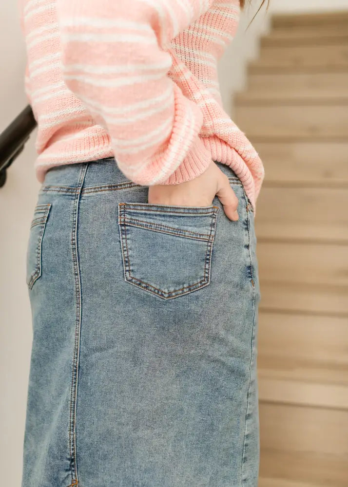 A mid-thigh length light blue wash denim skirt with visible stitching and classic back pocket design shown from the back