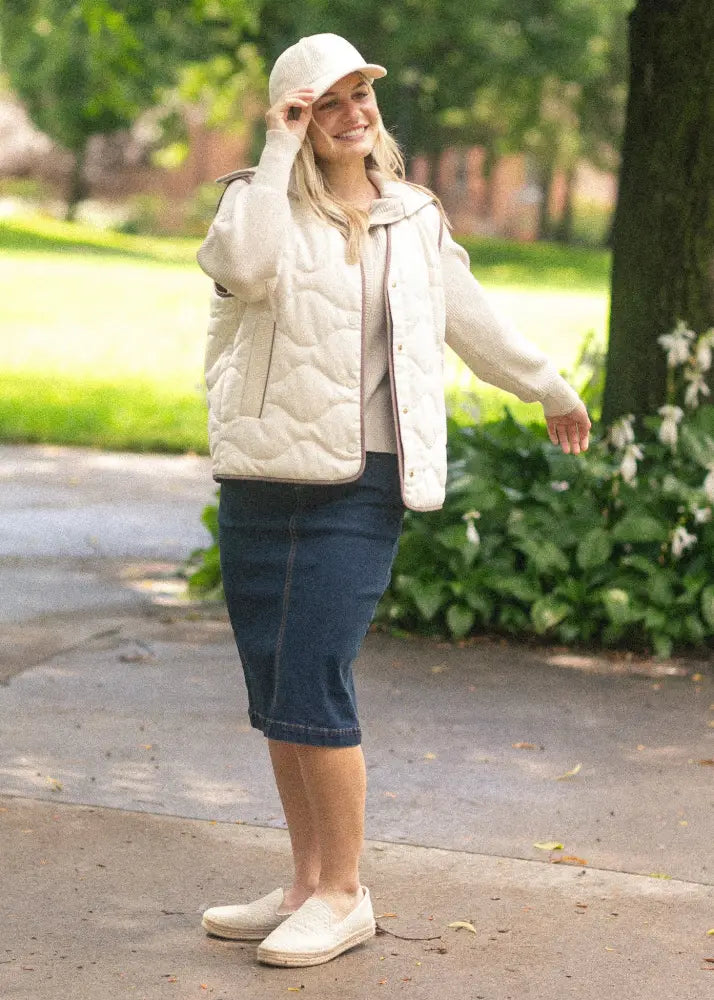 Cream-colored quilted puffer vest with soft padded texture paired with Sandra dark wash denim midi pencil skirt