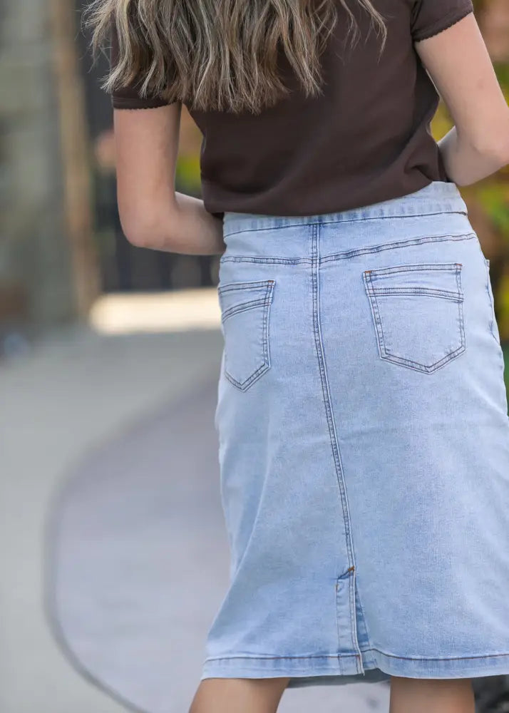 Back view of sandra light wash denim stretch midi skirt with two back pockets and central zipper closure