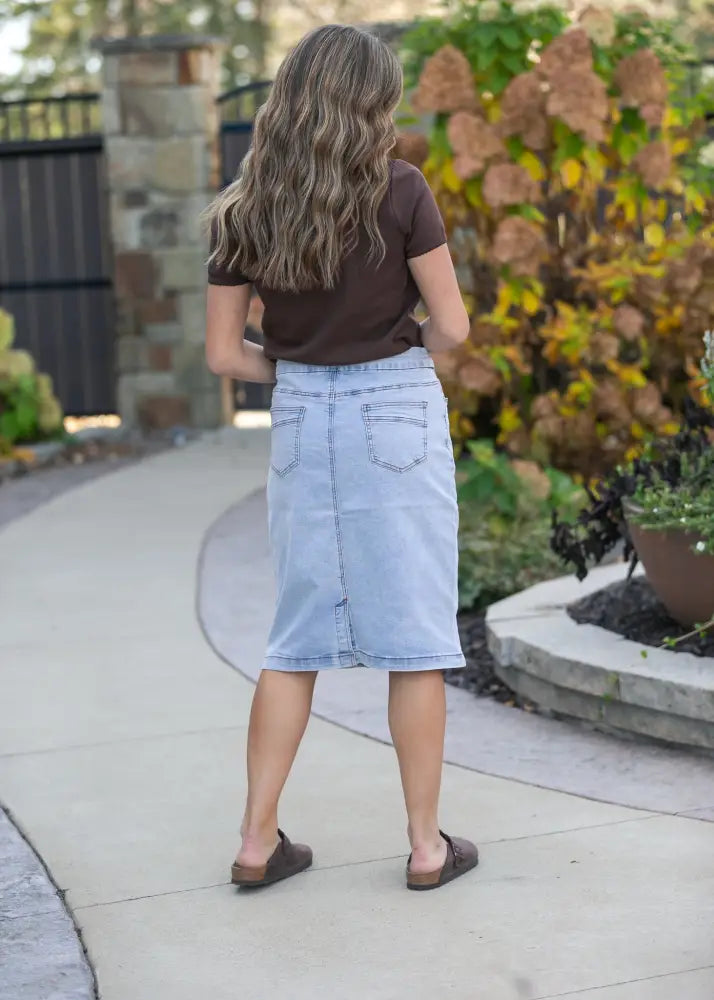 Back view of sandra light wash denim stretch midi skirt in light blue with two back pockets and a straight hemline