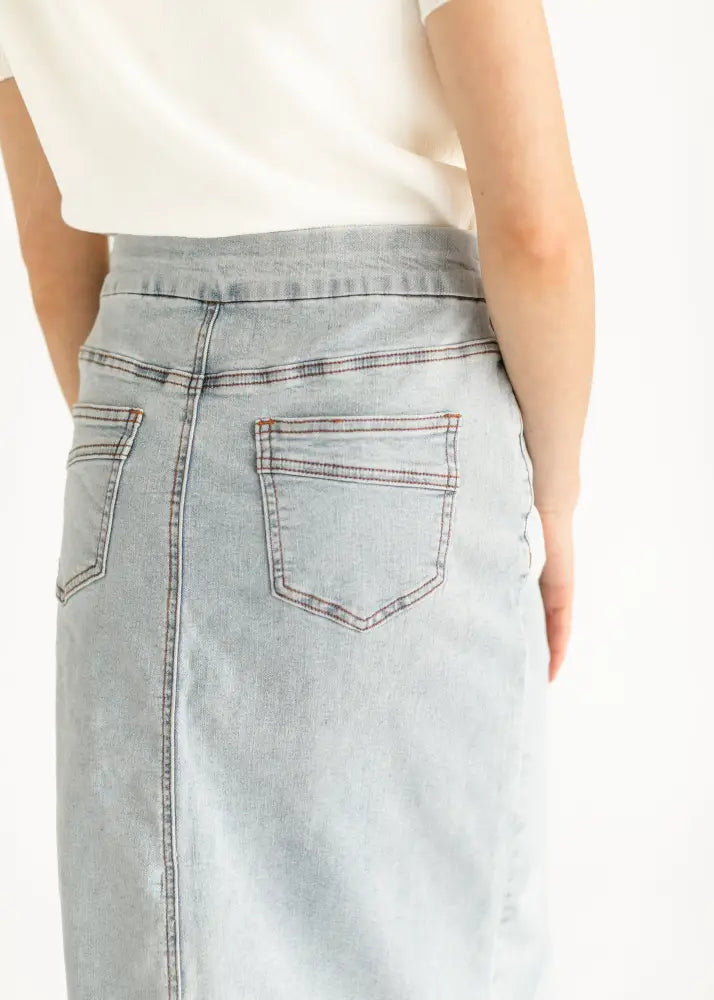 Back view of sandra light wash denim stretch midi skirt featuring two back pockets and contrasting stitching
