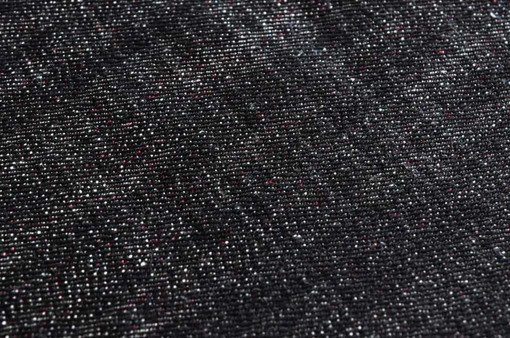 Dark denim fabric with subtle white and faint red speckled texture of Saucezhan Fire Selvedge tapered raw denim jeans