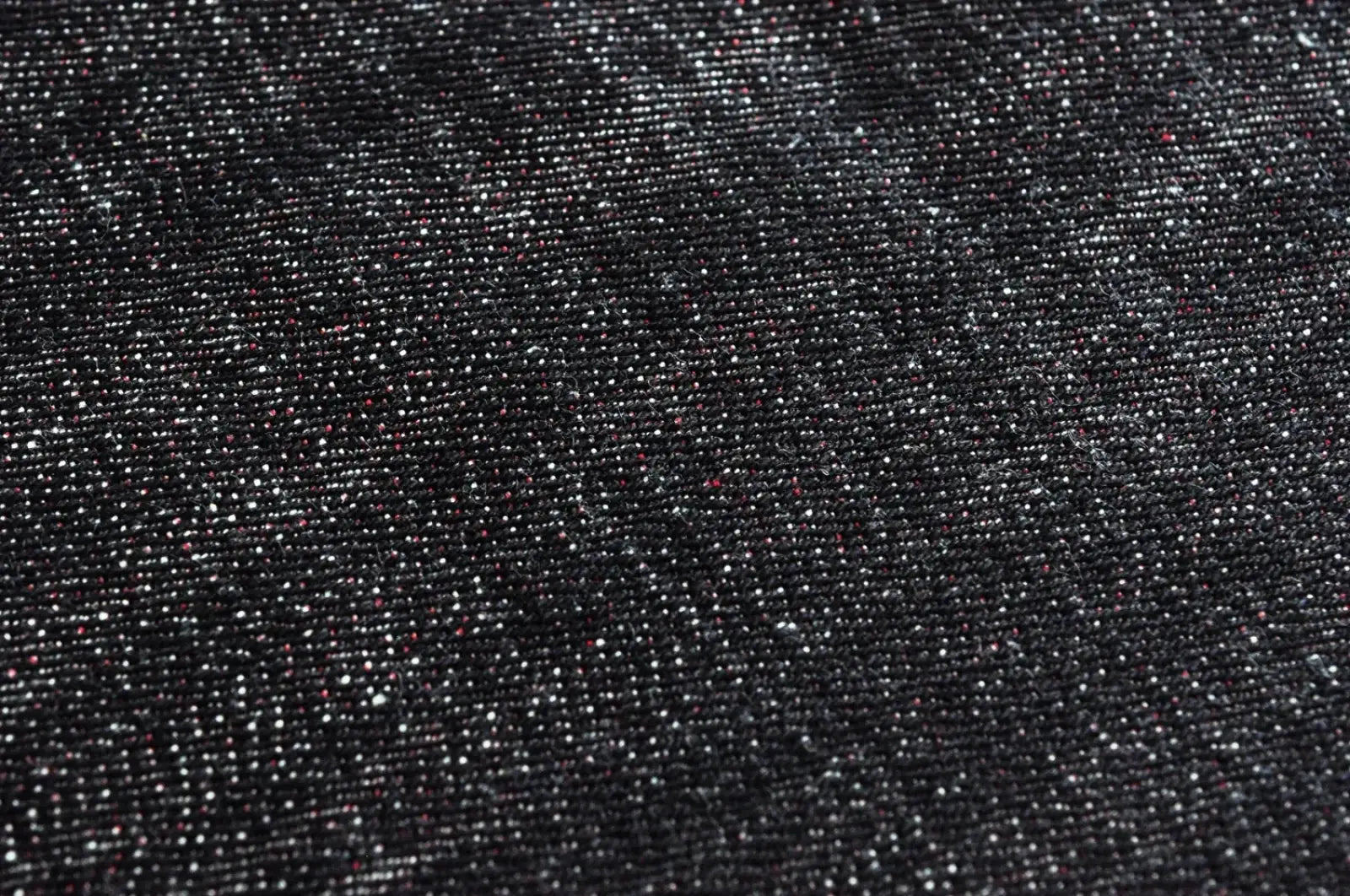 Dark denim fabric with subtle white and faint red speckled texture of Saucezhan Fire Selvedge tapered raw denim jeans